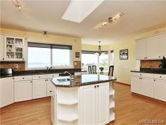 a large kitchen with white cabinets and black counter tops, along with an island in the middle