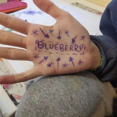 a person's hand with the word blueberry written on it in purple ink