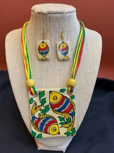 This piece of traditional Indian jewelry is known as terracotta. Made from clay, it is modeled into a shape then baked. It is then painted on, and terracotta pieces can depict anything from real images to abstract patterns.  This certain piece has beautiful and colorful  fish designs and comes with equally gorgeous matching earrings. All Terracotta products are hand-made jewelry. Each piece is hand painted by the artisans and there might be some slight discrepancy in terms of symmetry of the des Handmade Jewelry Indian, Clay Jewellery Designs, Terracotta Products, Terracotta Jewellery Making, Terracotta Art, Fish Designs, Motifs Design, Terracotta Jewellery Designs, Diy Jewelry Set