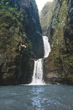 a man jumping off the side of a waterfall into a body of water