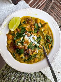 a white bowl filled with soup next to a slice of lime on top of a table