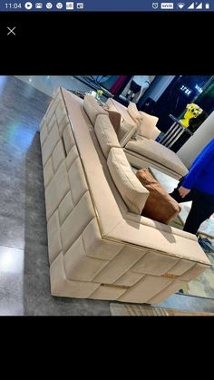 a white couch sitting on top of a wooden floor next to a person in a blue shirt