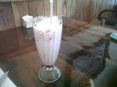 a smoothie is sitting on a table with a straw in the glass and it's ready to be eaten