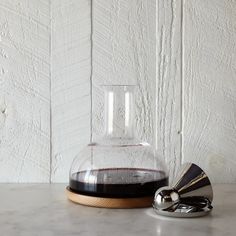 a glass vase sitting on top of a counter next to a metal object with a wooden base