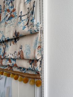 a close up of a roman blind with horse and flowers on it, in front of a white wall