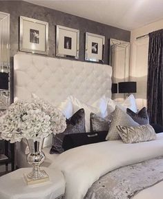 a white bed sitting in a bedroom next to two lamps and pictures on the wall