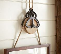 an old pair of scissors hanging on a rope next to a mirror and wooden frame