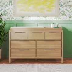 a bathroom with green walls and a wooden dresser next to a painting on the wall