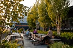 people are sitting at tables in the middle of an outdoor area with trees and plants