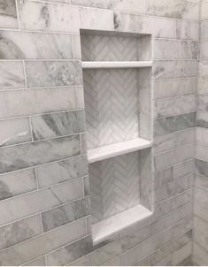 a white marble shower with shelves in it