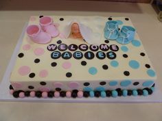 a welcome baby cake is decorated with blue and pink shoes, polka dot dots, and the words welcome babies