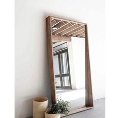 a mirror sitting on top of a wooden shelf next to a potted plant