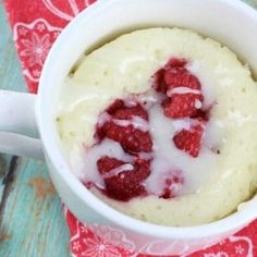 a white bowl filled with mashed potatoes and raspberries on top of a table