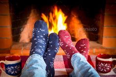 two people with socks and mugs are sitting in front of the fireplace - stock photo - images