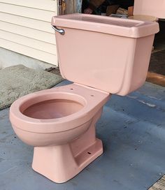 a pink toilet sitting in front of a house