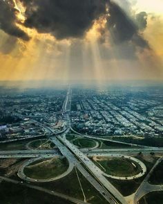 an aerial view of a highway intersection with sun rays coming through the clouds over it