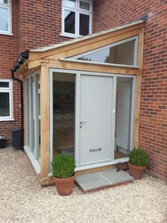 a small house with two potted plants in front of it and an open door