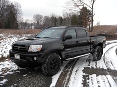 a black truck driving down a snow covered road