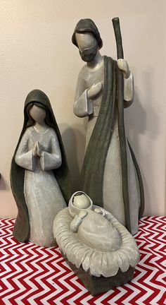 two ceramic figurines sitting on top of a red and white table cloth