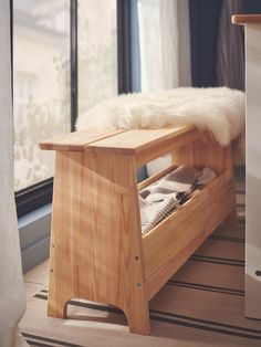 a wooden bench sitting in front of a window next to a white blanket on top of a rug