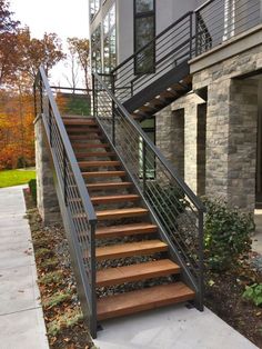 a metal stair rail with wood steps next to a brick wall and stone building in the background