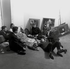 black and white photograph of people sitting on the floor in front of art work,