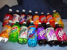 many different flavored sodas lined up on a bed