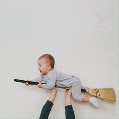 a man holding a baby on top of a broom while flying through the air with it's mouth