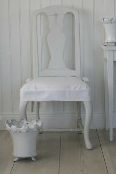 a white chair sitting next to a table with a basket on it's side