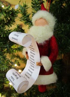 a santa clause ornament hanging on a christmas tree with a sheet of paper