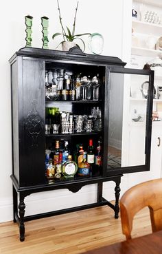 a black cabinet filled with lots of bottles and glasses