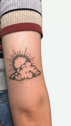 a woman's arm with a small sun and cloud tattoo on the left forearm