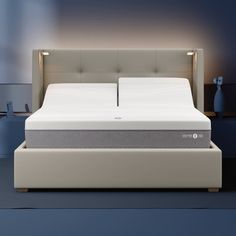 a bed with a white headboard and mattress in a blue room next to a night stand