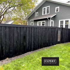 a black fence in front of a gray house with the expert logo on it