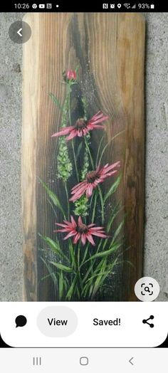 a wooden plaque with pink flowers and green leaves on it's side, hanging on the wall