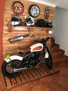 a motorcycle is parked in front of a wooden wall with many different items on it