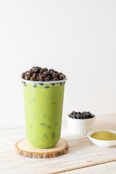 a green drink with raisins in it sitting on a table next to two bowls