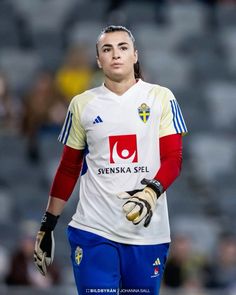 a female soccer player is walking on the field with her gloved hand in front of her face