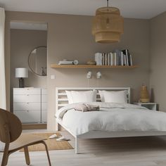 a white bed sitting in a bedroom next to a wooden shelf filled with lots of books