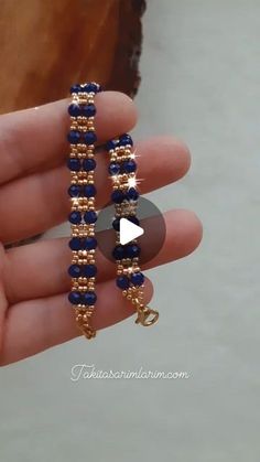 a person is holding two gold and blue beaded bracelets