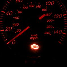 an illuminated speedometer in the dark with red numbers