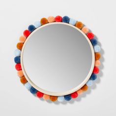 a round mirror with multi colored pom - poms on the bottom and sides