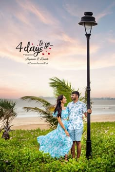 a man and woman standing next to each other under a lamp post on the beach