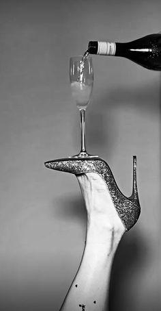 black and white photograph of a wine glass being poured into a snail shaped bottle holder