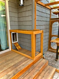 a wooden deck with a cage on top of it next to a door and window