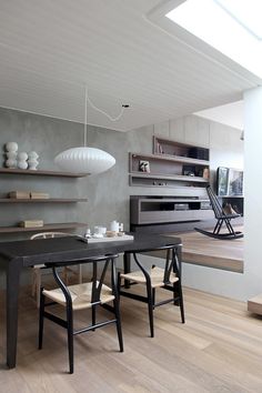 a dining room table with two chairs next to it and shelves on the wall behind it