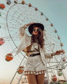 a woman standing in front of a ferris wheel with her hands on her hips and wearing sunglasses