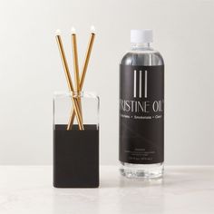 a bottle of puree oil next to a glass container with reeds in it