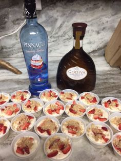 several desserts are arranged on a table with a bottle of gin