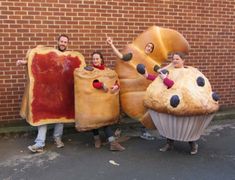 three people in costumes holding up giant donuts and large hotdogs with ketchup on them